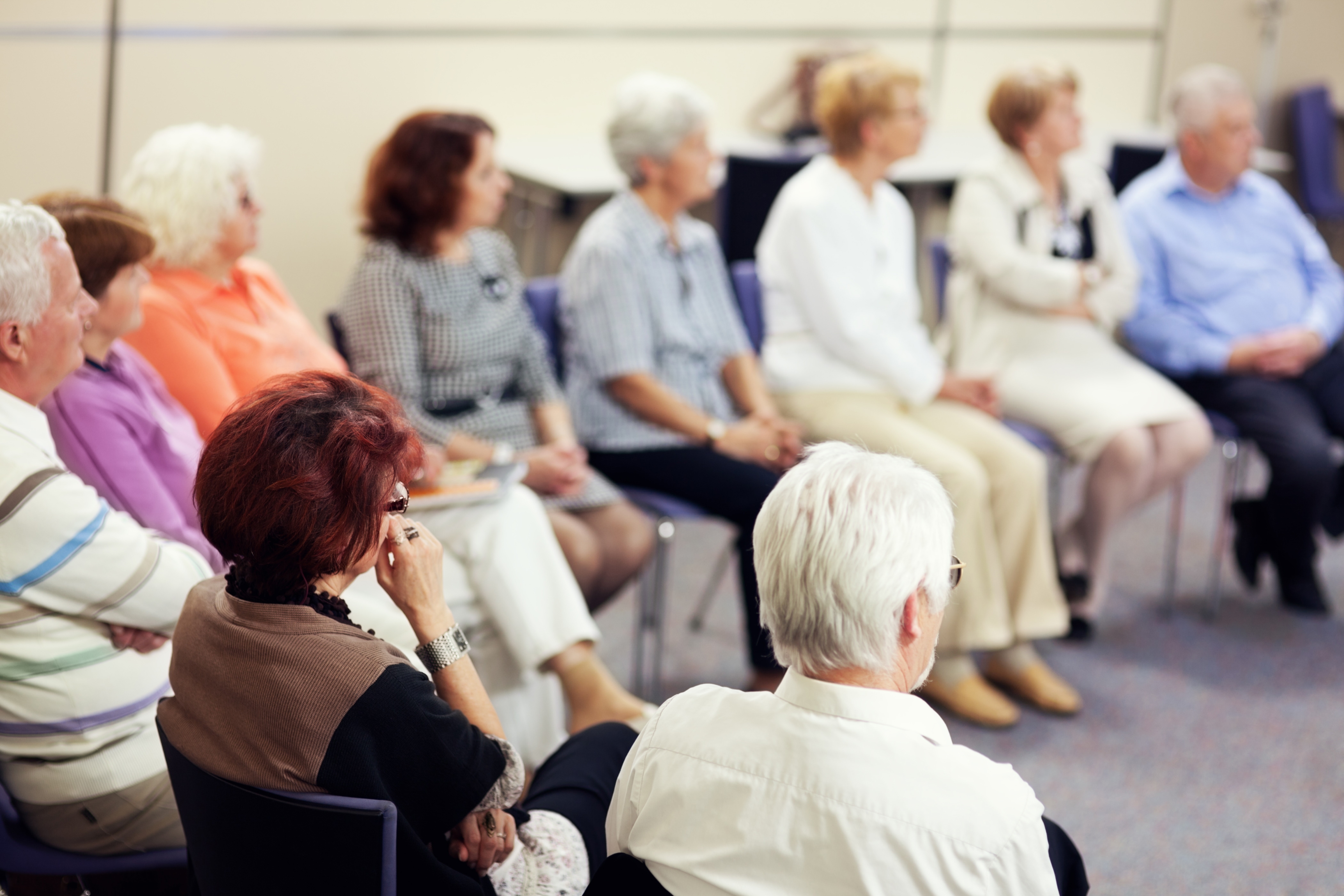 Auf dem Foto ist eine Gruppe von Seniorinnen und Senioren zu sehen, die in einem Stuhlkreis beisammen sitzen und einen Vortrag verfolgen.