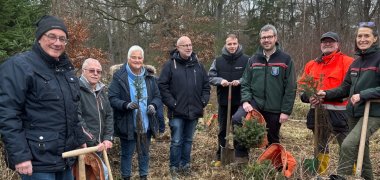 Männer und Frauen im Wald mit Spaten in der Hand.