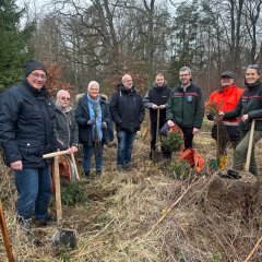 Männer und Frauen im Wald mit Spaten in der Hand.