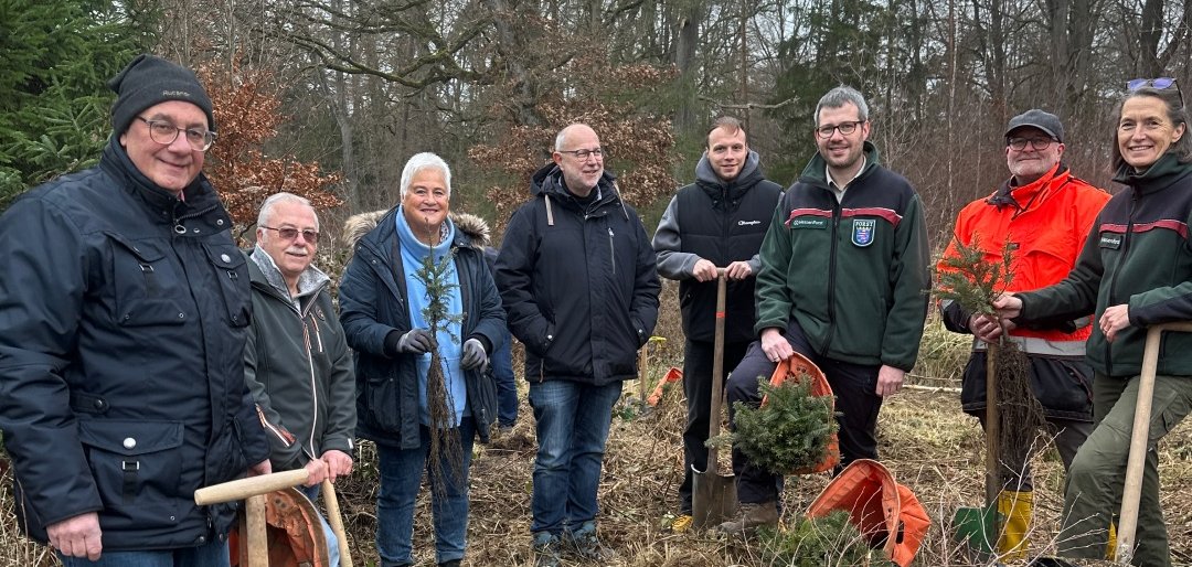 Männer und Frauen im Wald mit Spaten in der Hand.
