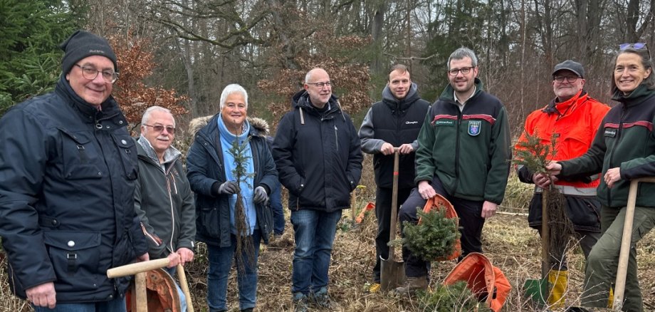 Männer und Frauen im Wald mit Spaten in der Hand.