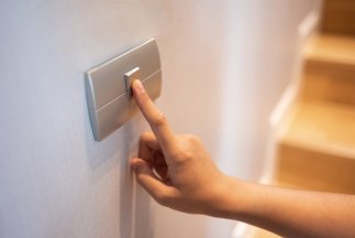 Nahaufnahme eines Fingers, der einen Lichtschalter im Haus ein- oder ausschaltet.