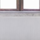 Heizkörper unter dem Fenster mit Holzrahmen und Vorhängen.