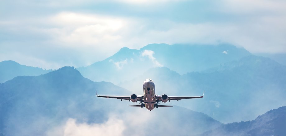 Jet-Flugzeug im Himmel über erstaunliche blauen nebligen Bergen.