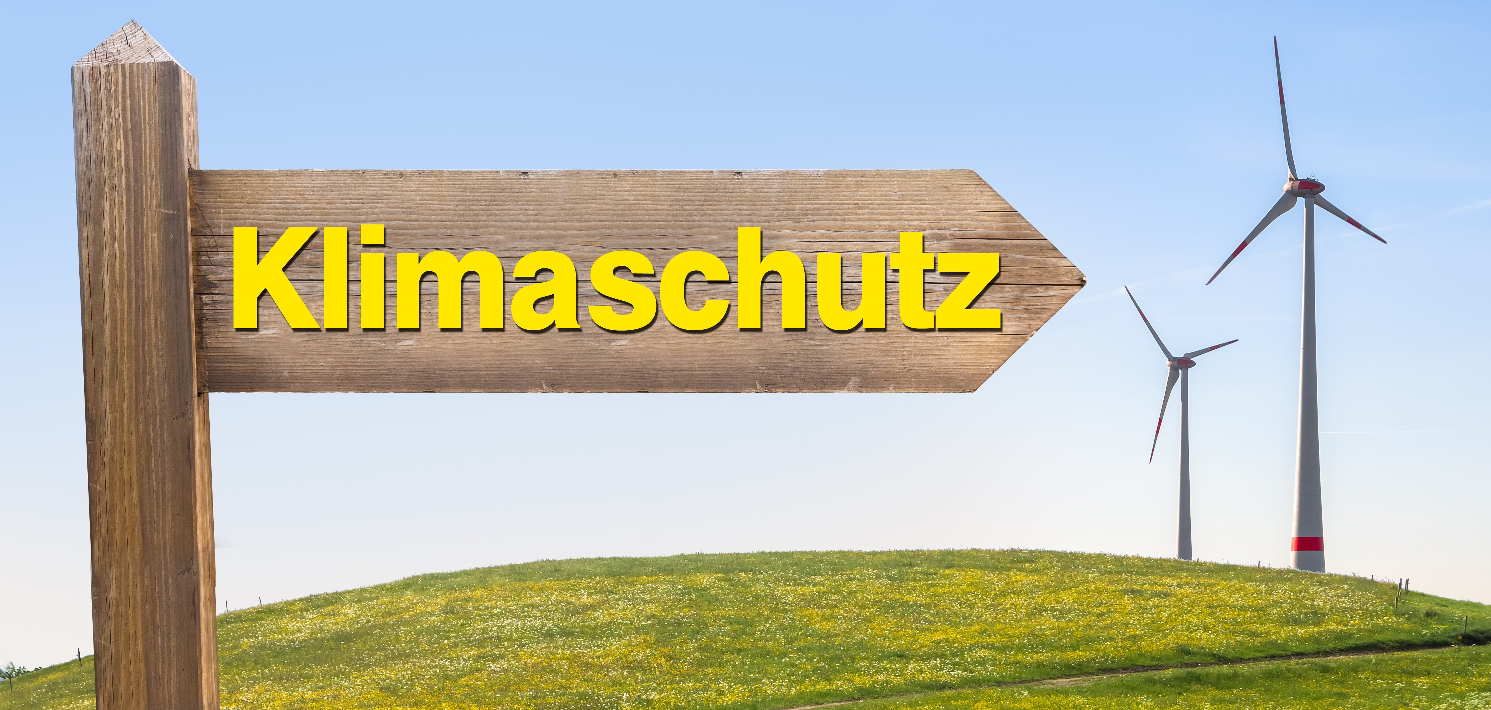 Schild mit dem Wort Klimaschutz und Windrädern im Hintergrund