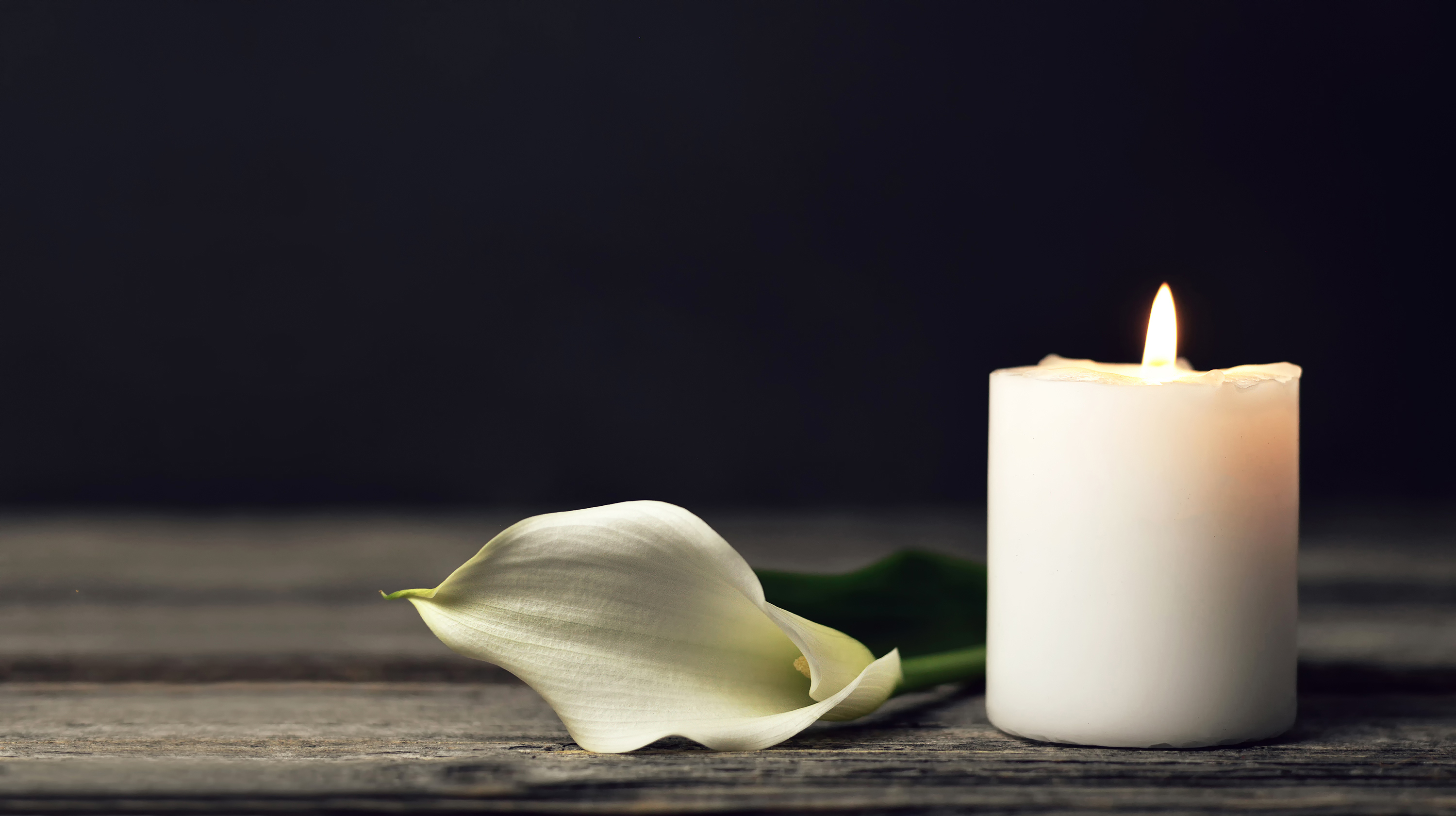 Burning candle and white calla on dark background with copy space. Sympathy card Burning candle and white calla on dark background with copy space. Sympathy card