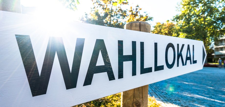Schild auf dem "Wahllokal" steht mit Sonne im Hintergrund.