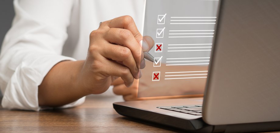 Ein Geschäftsmann macht ein Häkchen und ein Kreuzsymbol auf einem Dokumentenmanagementsystem oder DMS auf einem virtuellen Bildschirm. Bewertungsformular, Fragebogen und Checklistenverwaltung