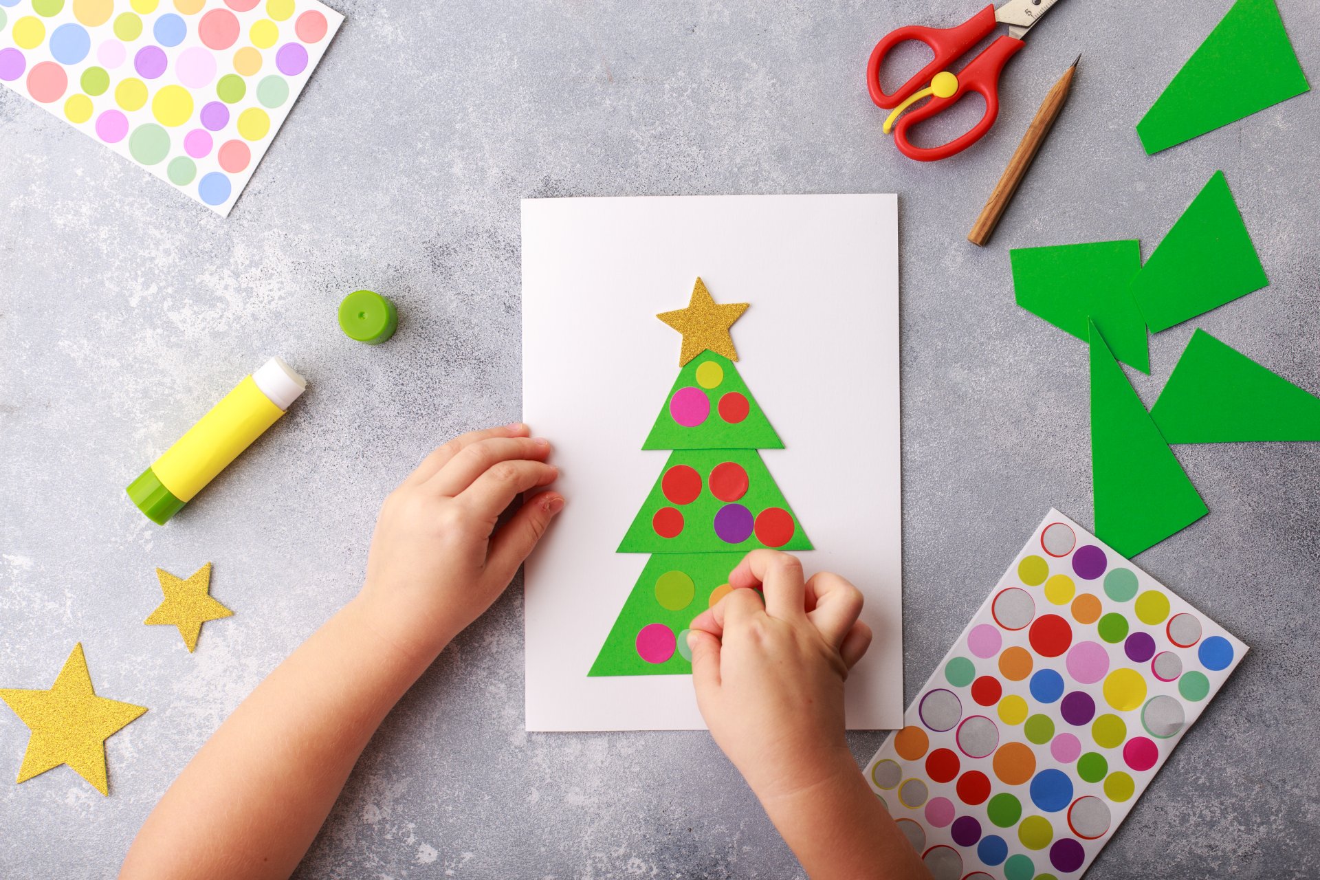 The child makes a greeting card Christmas paper collage. Children's art project craft for kids. Craft for children. Top view The child makes a greeting card Christmas paper collage. Children's art project craft for kids. Craft for children. Top view