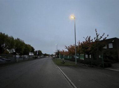 Dunkle Straße mit einer hellen Laterne.