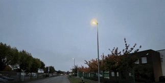Dunkle Straße mit einer hellen Laterne.