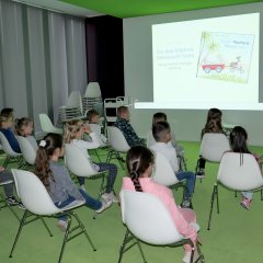 Die Büchereimitarbeiterin Michaela Fenn (r.) liest den Kindern ein animiertes Bilderbuchkino vor.