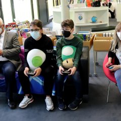 Bürgermeister Uwe Jäger (l.) spielt gemeinsam mit den Schülern Darius Tripa, Alexander Tenz und der Büchereimitarbeiterin Louisa Theis Nintendo Switch.